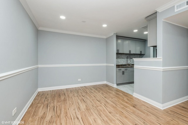 interior space featuring light wood finished floors, baseboards, gray cabinets, and backsplash