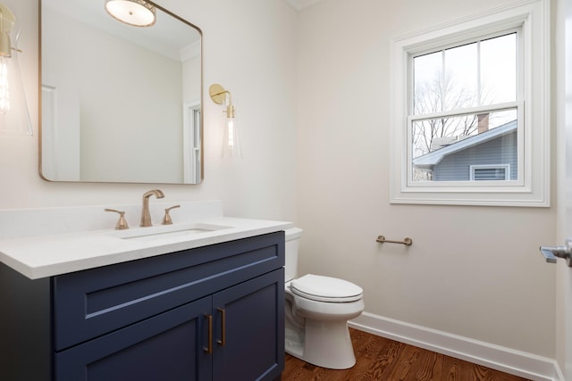 bathroom with toilet, vanity, baseboards, and wood finished floors