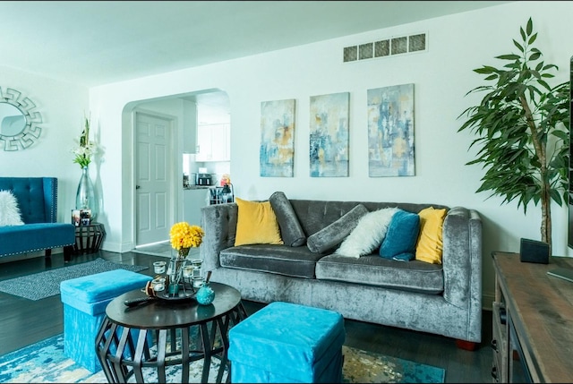 living room featuring arched walkways, wood finished floors, and visible vents