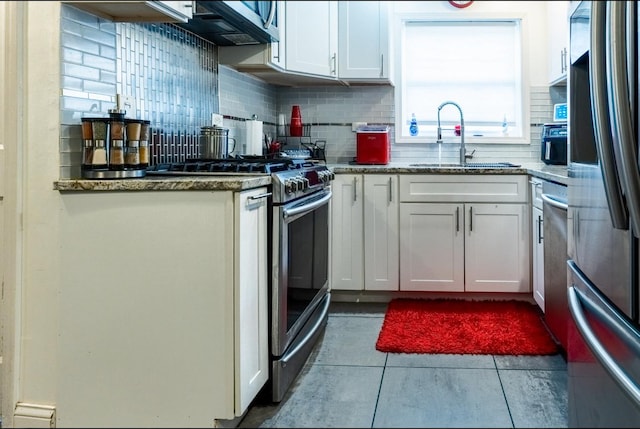 kitchen featuring a sink, white cabinets, appliances with stainless steel finishes, decorative backsplash, and tile patterned floors