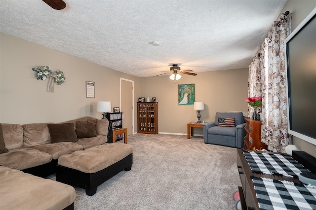 living area with a ceiling fan, light carpet, a textured ceiling, and baseboards