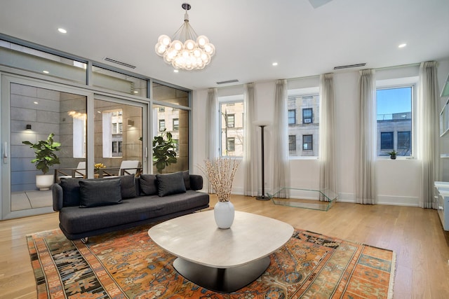 living room featuring a chandelier, light wood-type flooring, visible vents, and recessed lighting