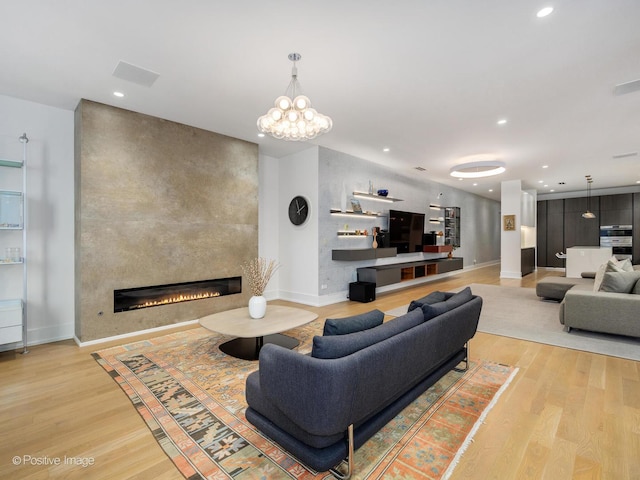 living area with baseboards, light wood-style floors, a fireplace, a notable chandelier, and recessed lighting