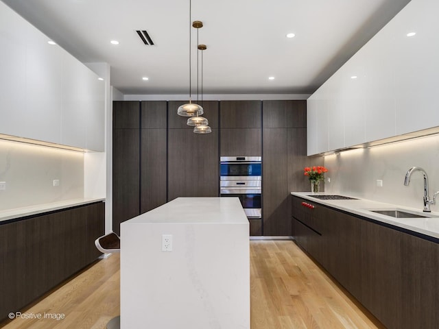 kitchen with double oven, a sink, visible vents, dark brown cabinets, and modern cabinets