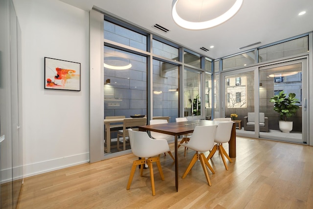 dining room featuring a wall of windows, visible vents, light wood-style floors, and baseboards