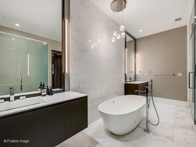 bathroom with marble finish floor, tile walls, recessed lighting, vanity, and a freestanding tub