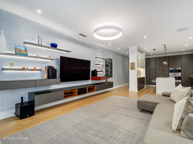 living area featuring light wood-type flooring, visible vents, and recessed lighting