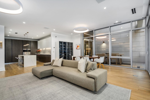 living room with visible vents, light wood-style flooring, and recessed lighting