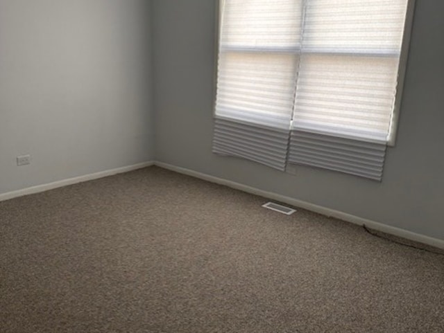 carpeted empty room featuring visible vents and baseboards