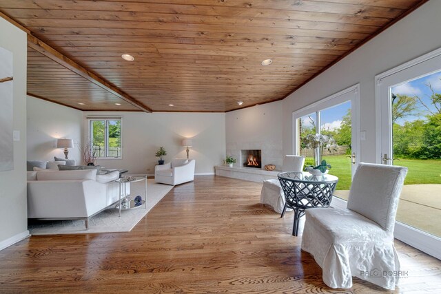 living area with recessed lighting, wood ceiling, wood finished floors, a warm lit fireplace, and baseboards