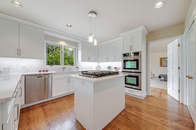 kitchen with stainless steel appliances, light wood-style floors, a kitchen island, and white cabinets