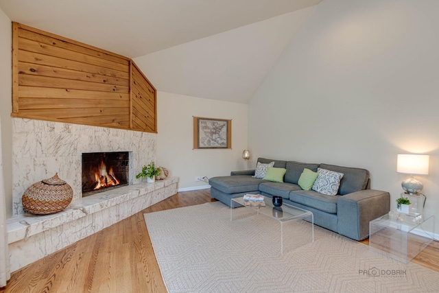 living room featuring high vaulted ceiling, a fireplace, baseboards, and wood finished floors