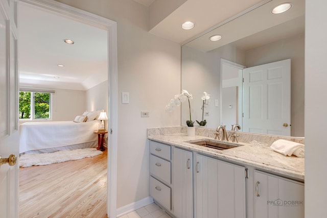 bathroom featuring baseboards, wood finished floors, vanity, and recessed lighting