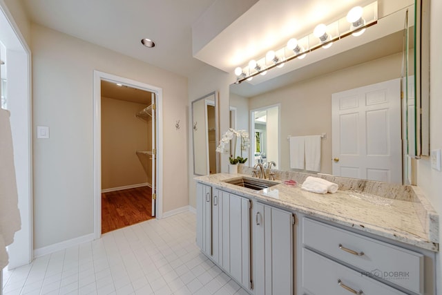 full bath with baseboards, tile patterned floors, a walk in closet, vanity, and recessed lighting