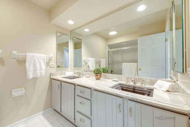 bathroom featuring a stall shower, tile patterned flooring, a sink, and baseboards