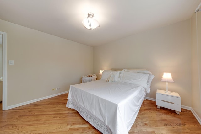 bedroom featuring light wood finished floors and baseboards