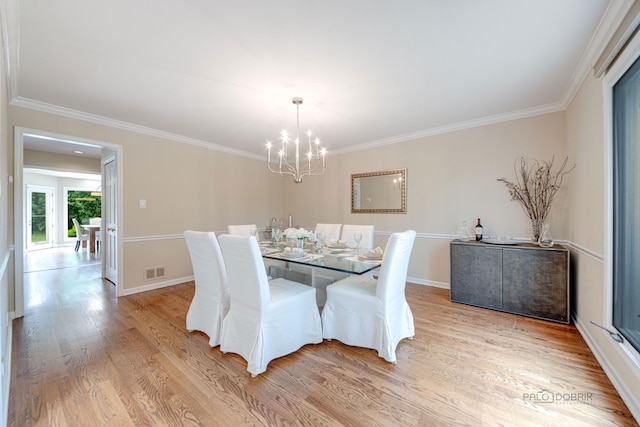 dining room with a chandelier, light wood finished floors, ornamental molding, and visible vents