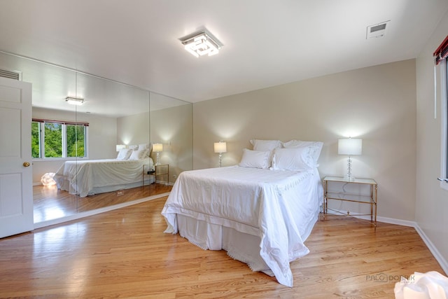 bedroom with wood finished floors, visible vents, and baseboards