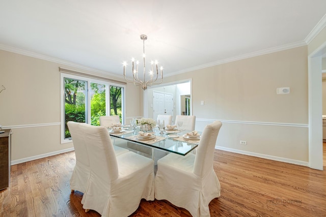 dining area with a notable chandelier, crown molding, baseboards, and wood finished floors