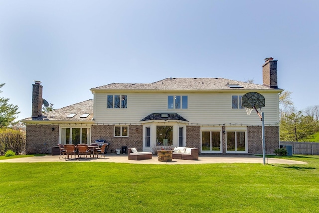 back of house featuring a patio area, a chimney, a lawn, and brick siding