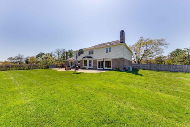 back of house with brick siding, central air condition unit, a lawn, a patio area, and fence