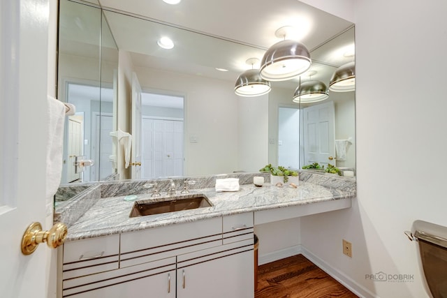 bathroom featuring wood finished floors, vanity, and baseboards