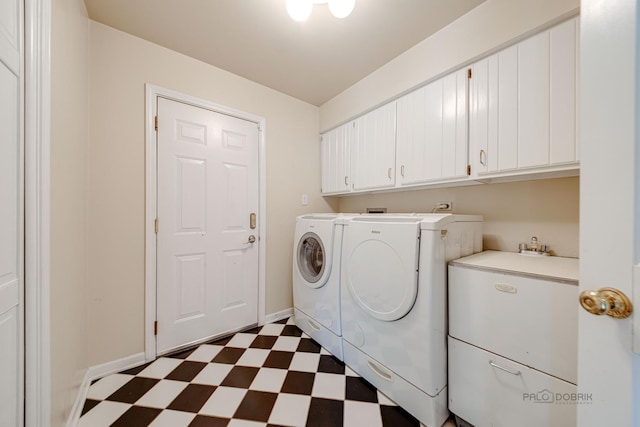 laundry area with dark floors, cabinet space, baseboards, and separate washer and dryer