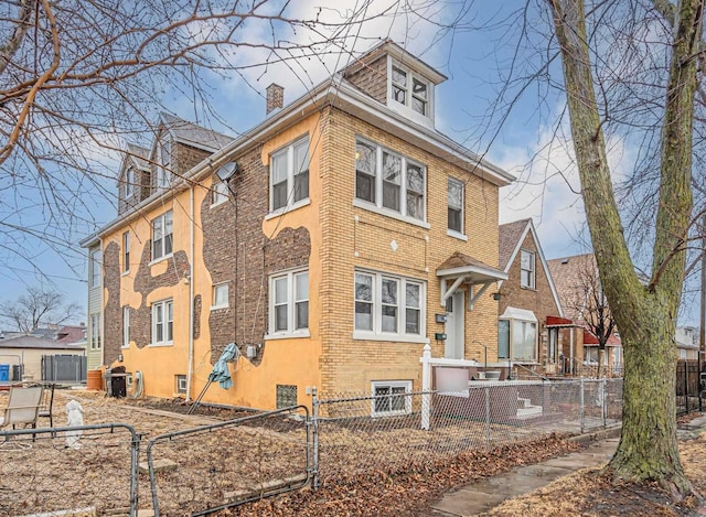 view of front of house featuring a fenced front yard, brick siding, and a chimney