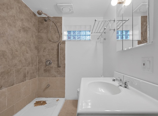 bathroom featuring tiled shower, a sink, and toilet