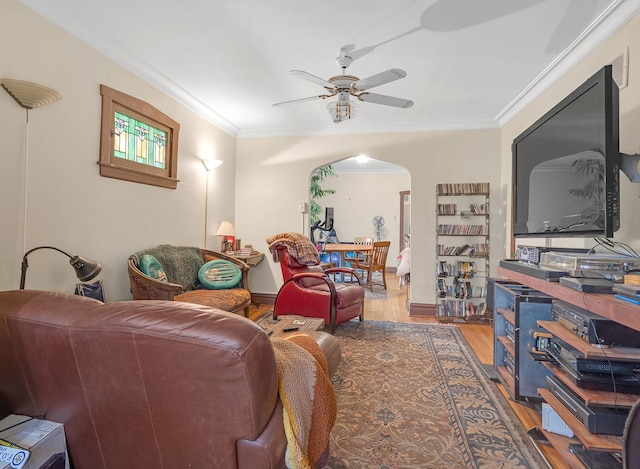 living area featuring arched walkways, ceiling fan, wood finished floors, and crown molding