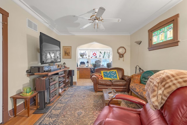 living area with crown molding, visible vents, ceiling fan, wood finished floors, and baseboards