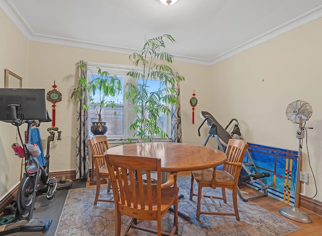 dining room featuring crown molding, baseboards, and wood finished floors