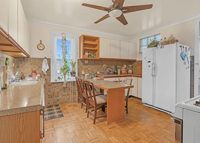 kitchen with open shelves, ornamental molding, freestanding refrigerator, a sink, and a kitchen bar