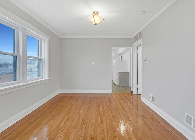 unfurnished room with light wood-style flooring, visible vents, and crown molding