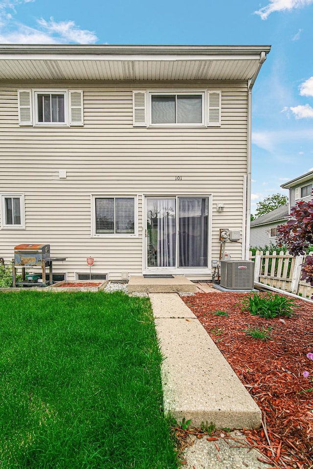 back of house featuring a lawn, fence, and central AC unit