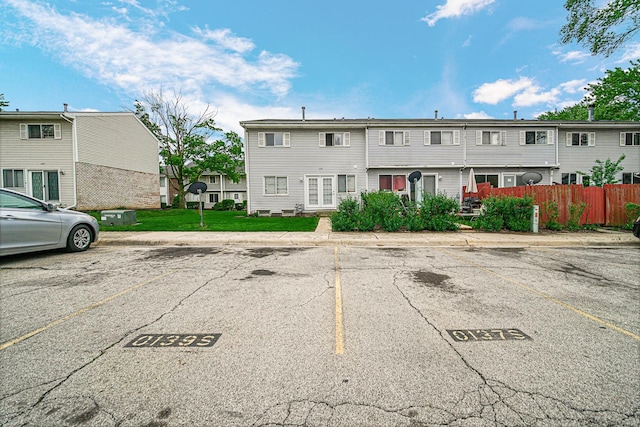 view of front of house featuring uncovered parking, fence, and a front lawn