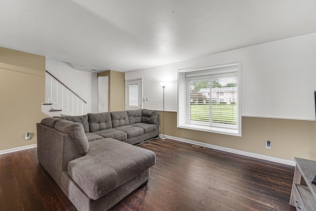 living room featuring stairs, visible vents, baseboards, and wood finished floors