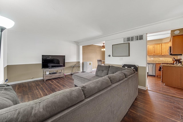 living area featuring visible vents, dark wood finished floors, and baseboards