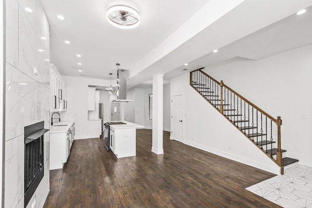 kitchen with range hood, dark wood finished floors, recessed lighting, a sink, and stainless steel gas range