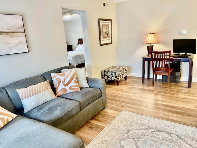 living area with light wood finished floors, visible vents, and baseboards