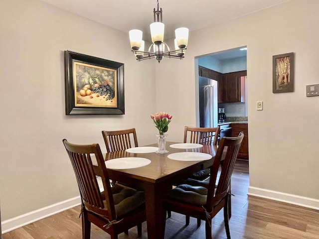 dining space featuring a notable chandelier, wood finished floors, and baseboards