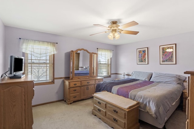 bedroom with ceiling fan, baseboards, and light colored carpet