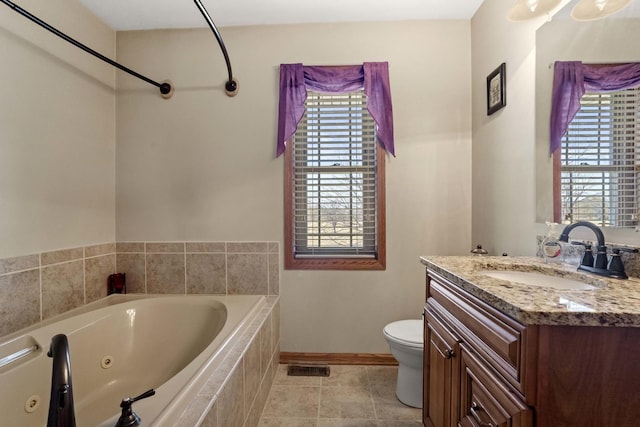 bathroom featuring a whirlpool tub, a healthy amount of sunlight, toilet, and vanity