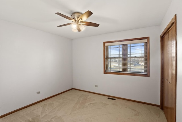 unfurnished bedroom featuring light colored carpet, a ceiling fan, baseboards, visible vents, and a closet