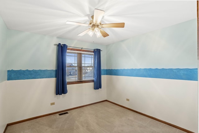 carpeted empty room featuring baseboards, visible vents, and a ceiling fan