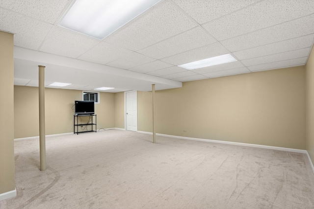 finished below grade area featuring carpet floors, a paneled ceiling, and baseboards