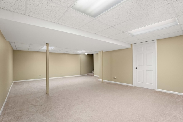 finished below grade area with carpet floors, a paneled ceiling, baseboards, and stairs