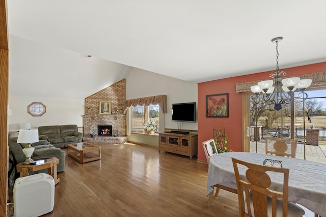 interior space with lofted ceiling, a brick fireplace, plenty of natural light, and wood finished floors