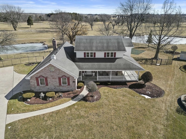 view of front of house featuring a chimney, a water view, covered porch, a front yard, and brick siding