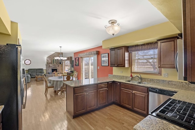 kitchen with plenty of natural light, a peninsula, stainless steel appliances, light wood-type flooring, and a sink